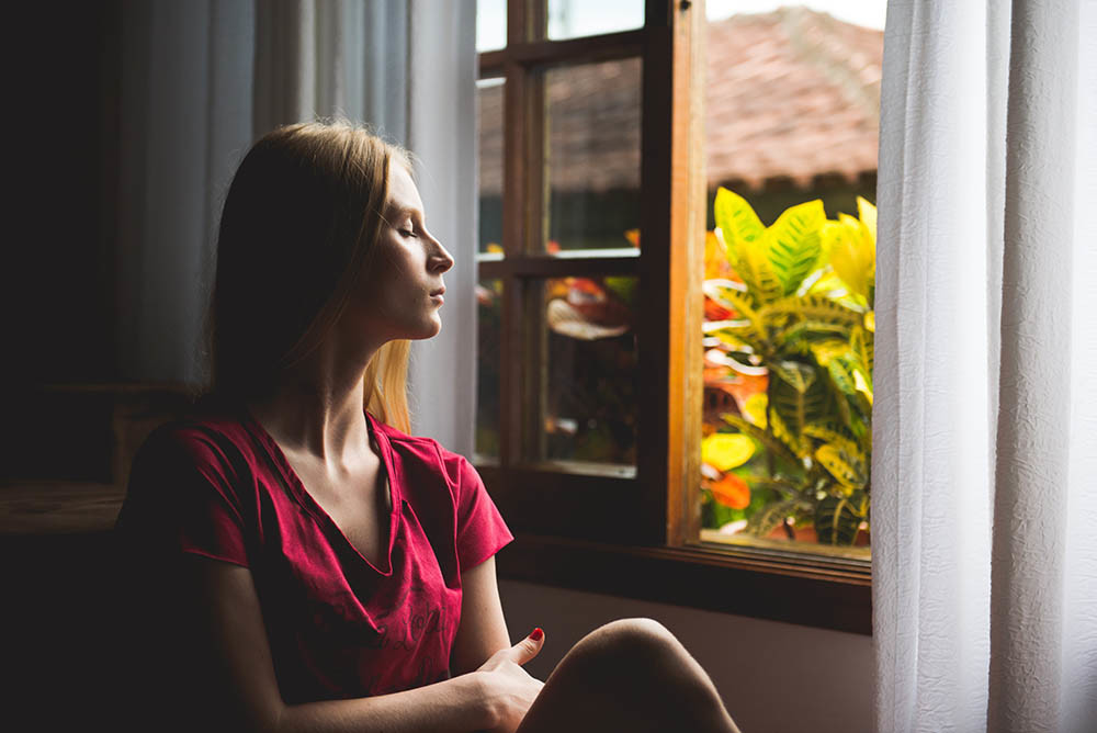 Donna Relax alla finestra meditando e controllando respiro